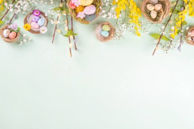 Paskalya yuvaları ve bahar çiçekli yumurtalar, Mutlu Paskalya bayramı tebrik kartları açık yeşil bahar arka planında yatıyordu, üst görünüm kopyalama alanı