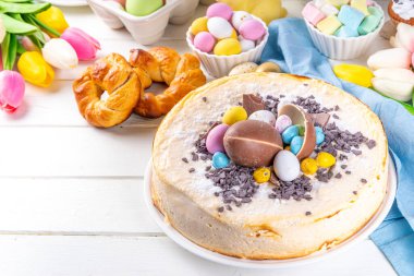 Homemade Easter cheesecake, sweet cottage cheese baking, with Ester chocolate eggs and chocolate drops, with holiday decorations and spring flowers