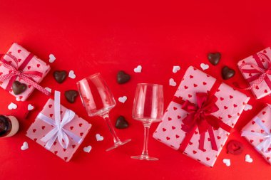 Sevgililer Günü tebrik kartı geçmişinde çikolata kalpler, hediye kutuları, şarap kadehleri ve kırmızı arka planda şişe var. Sevgililer günü restoran, kafe ve parti davetiyesi menüsü.