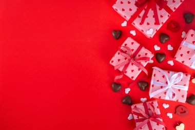 Sevgililer Günü tebrik kartı geçmişinde çikolata kalpler, hediye kutuları, şarap kadehleri ve kırmızı arka planda şişe var. Sevgililer günü restoran, kafe ve parti davetiyesi menüsü.
