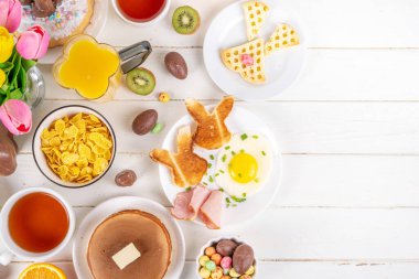 Paskalya tatili tatlı kahvaltı, brunch. Paskalya süslü Belçika waffle 'ları, krepler, kahvaltı gevrekleri ve süt, kızarmış yumurtalar kızarmış ekmek ve pastırma, Paskalya çikolatalı yumurtalar ve bahar çiçekleriyle birlikte tavşan.