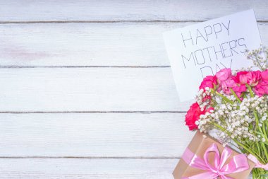 Anneler günü tebrik kartı, davetiye arkaplanı, güzel ranunculus çiçeği buketi, sevimli el işi kağıt hediye paketi ve not: Mutlu anneler günleri, beyaz arkaplanda kopyalama alanı