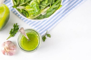 Mutfak aromalı yeşil sebze salatası sosu. Akşam yemeği için maydanoz sarımsaklı zeytinyağı ve mutfak arka planında yeşil salata.