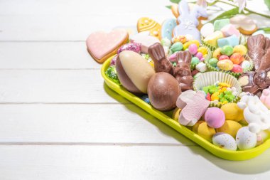 Easter charcuterie board. Sweet Easter party, kids holiday treats assortment - chocolates, easter eggs, marshmallows, candies, chocolate bunny, snacks and treats tray