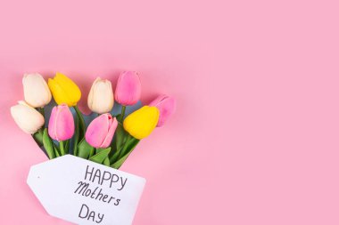 Anneler gününde lale çiçeği buketi, pembe kurdeleli hediye kutusu ve mutlu anneler günü etiketi. Tebrik kartı arkaplanı, poster, broşür, broşür, tanıtım malzemeleri, web sitesi