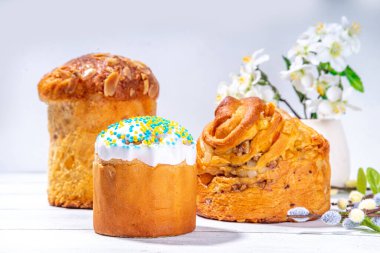 Geleneksel tatil pastaları ile Paskalya pastaları - Kraffin, panettone, paska kulich, Paskalya yumurtaları, beyaz ahşap masa üzerinde bahar çiçekleri, bahar bayramı Paskalya tebrik kartı arka planı