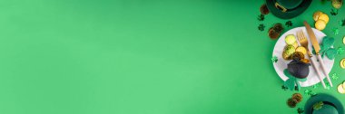 Aziz Patrick Günü şenlik masası. Tabak ve çatal bıçak takımı, altın paralar, leprikon kap, şans için yonca dekoru. Patrick Day menüsü, yeşil arkaplan, parti daveti, üst görünüm kopyalama alanı