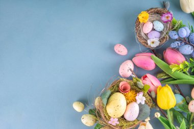 Bahar Paskalya bayramı masası boyalı Paskalya yumurtaları, bahar çiçekleri buketi, dekoratif tavşanlar, beyaz mutfak arka planında 