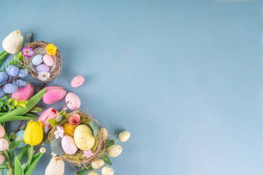 Bahar Paskalya bayramı masası boyalı Paskalya yumurtaları, bahar çiçekleri buketi, dekoratif tavşanlar, beyaz mutfak arka planında 