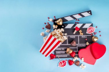 14 Şubat Sevgililer Günü 'nde romantik bir randevu. Aşk filmi maratonu, sinema salonunda randevu. Kırmızı zemin üzerinde el çırpma tahtası, patlamış mısır kovaları, kalp dekorasyonu ve çikolatalar.