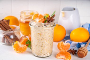 Mandalina kremalı bir gecelik yulaf ezmesi, kremalı yulaf ezmesi ve taze mandalina dilimleri, baharatlar ve portakal kabuğu.