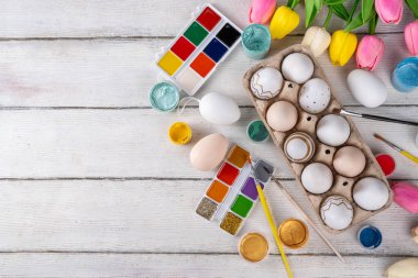 Aile gelenekleri, Paskalya hazırlıkları. Bahar çiçeği laleleri, dekoratif Paskalya yumurtaları boyalı, fırçalı, aksesuarlı beyaz ahşap arka planda yumurta çizip boyamak için aksesuarlar.