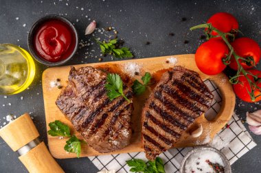 Ahşap kesme tahtasında ızgara biftek, ketçap sosu ve baharat, üst görünüm kopya alanı.