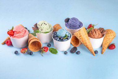 Renkli arka planda waffle konileri ve böğürtlenlerle dolu renkli, parlak dondurmalar. Taze böğürtlenli farklı aromalı dondurma porsiyonları üst görünüm kopya alanı arka planı