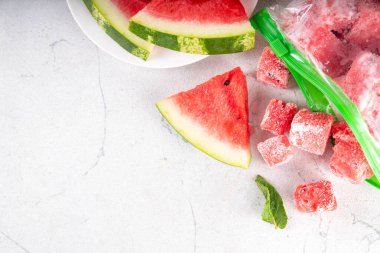 Donmuş karpuz dilimleri, donmuş poşetlerdeki taze çiğ karpuzlar mutfak masasındaki beyaz masa, sağlıklı basit konserve, kış konsepti için dondurulmuş meyve hasadı stokları.. 