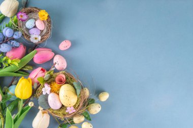 Bahar Paskalya bayramı masası boyalı Paskalya yumurtaları, bahar çiçekleri buketi, dekoratif tavşanlar, beyaz mutfak arka planında 