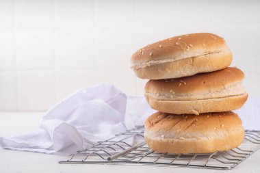 Ev yapımı taze pişmiş hamburger çörekleri. Geleneksel Amerikan susamlı çörekleri beyaz mutfak masasında.