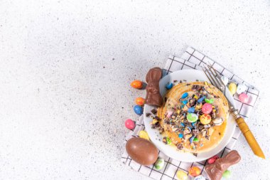 Paskalya için çocukların komik şirin kahvaltısı. Amerikan gözlemeleri, çikolatalı kızarmış hamur kekleri, çikolatalı yumurtalar, marşmelovlar, üzerine çikolata parçacıklı şeker serpiştirilmiş dekorlar.