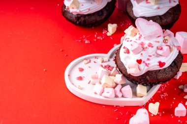 Valentine day tasty double chocolate cupcakes treat with whipped cream, heart shaped marshmallow and sugar sprinkles clipart