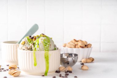 Dubai çikolatalı dondurma, tahini, kataifi ve çikolatalı dondurma, Dubai çikolatalı şurup soslu ve fıstıklı, beyaz mutfak masasında,