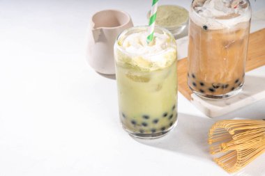 Klasik ve yeşil kibrit boba balonu çayı tapyoka incileri ve sütsüz krema bardağın üstünde, yaz aylarında tatlı tatlı içeceği beyaz masa arkasında fotokopi alanı