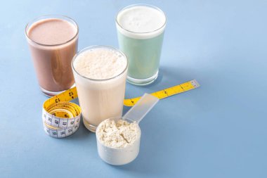 Protein tozu kepçesi ve mezurayla protein kokteyllerinin çeşitli çeşitleri. Protein, kilo vermek için sallanıyor, her gün protein hedefleri, spor ve spor, sağlıklı yaşam tarzı.
