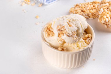 Pirinç gevreği dondurmayı, gevrek vanilyalı dondurmayı portakal kaselerinde, beyaz masa arkasında bolca pirinç gevreğiyle ikram eder.