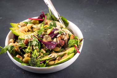 Bitki temelli keto yiyecekler, düşük karbonhidratlı vegan salatası çeşitli yeşil sebzeler, avokado, roka, ıspanak, marul, beyaz peynir, fındık, fıstık, fıstık ezmesi, avokado ve zeytin.