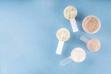 Plastik kepçelerde farklı protein tatları. Protein tozu kilo kaybı için sallanıyor, her gün protein hedefleri, spor ve spor, sağlıklı yaşam tarzı belirleniyor.