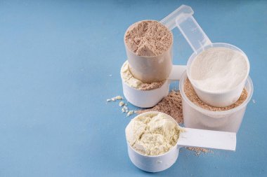 Plastik kepçelerde farklı protein tatları. Protein tozu kilo kaybı için sallanıyor, her gün protein hedefleri, spor ve spor, sağlıklı yaşam tarzı belirleniyor.