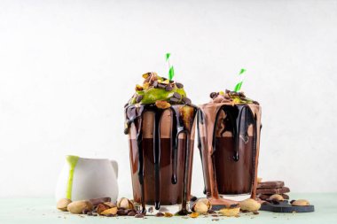 Dubai çikolatalı milkshake, çikolatalı kokteyl, çırpılmış çikolata kreması, kadaif şam fıstıklı parfe ve Dubai çikolata şurubu, çikolata damlalarıyla dolu, ezilmiş şam fıstığı.