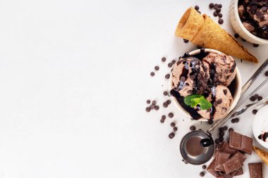 Beyaz masa arkasında dondurma külahlı duble çikolatalı dondurma kasesi. Ev yapımı çikolatalı dondurma ve çikolata sosu, tatlı ve lezzetli yaz tatlısı.