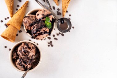 Beyaz masa arkasında dondurma külahlı duble çikolatalı dondurma kasesi. Ev yapımı çikolatalı dondurma ve çikolata sosu, tatlı ve lezzetli yaz tatlısı.