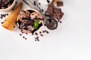 Beyaz masa arkasında dondurma külahlı duble çikolatalı dondurma kasesi. Ev yapımı çikolatalı dondurma ve çikolata sosu, tatlı ve lezzetli yaz tatlısı.