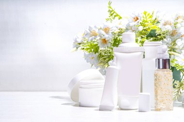 Foraged and wild-harvested beauty, Cosmetic skincare products on white background with wild grown flowers. Set white jars, tubes, droppers, bottles. Spa, daily organic natural skin care routine clipart