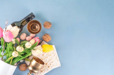 Bahar lale çiçekleri, dekoratif Paskalya yumurtaları, şarap şişesi ve cam, matzah yassı ekmek, fındık ve menoranın renklendirildiği Musevi bayramı arkaplanı.