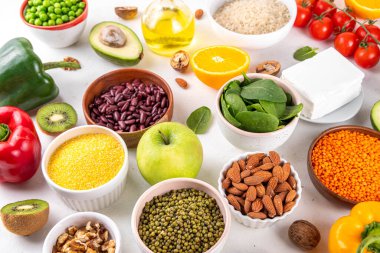 Portföy diyeti, fındık, sebze proteini, bitki sterolleri, yapışkan lif, fasulye, baklagiller, taze sebzeler ve beyaz arka plandaki meyveler dahil olmak üzere dengeli kolesterol vejetaryen gıdalar.