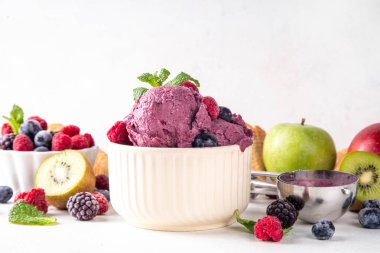 Ev yapımı meyve ve meyveli dondurma, sağlıklı meyve ve yoğurt ile porsiyonlu dondurma taze yaban mersini, ahududu, çilek, böğürtlen, elmalar, mutfak masasında kivi.