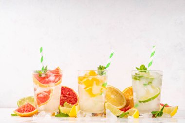 Yaz turunçgilleri arınma suyu, limon, limon, greyfurt, portakal, limonata, ahşap arka planda buzlu limonata içecekler. Buzlu mevsimlik içecek, meyve dilimleri ve naneli.