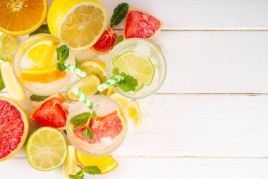 Yaz turunçgilleri arınma suyu, limon, limon, greyfurt, portakal, limonata, ahşap arka planda buzlu limonata içecekler. Buzlu mevsimlik içecek, meyve dilimleri ve naneli.