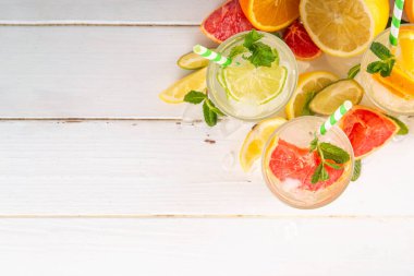 Yaz turunçgilleri arınma suyu, limon, limon, greyfurt, portakal, limonata, ahşap arka planda buzlu limonata içecekler. Buzlu mevsimlik içecek, meyve dilimleri ve naneli.