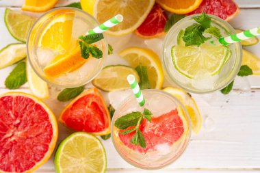 Yaz turunçgilleri arınma suyu, limon, limon, greyfurt, portakal, limonata, ahşap arka planda buzlu limonata içecekler. Buzlu mevsimlik içecek, meyve dilimleri ve naneli.