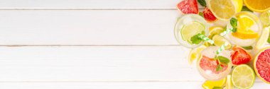 Yaz turunçgilleri arınma suyu, limon, limon, greyfurt, portakal, limonata, ahşap arka planda buzlu limonata içecekler. Buzlu mevsimlik içecek, meyve dilimleri ve naneli.
