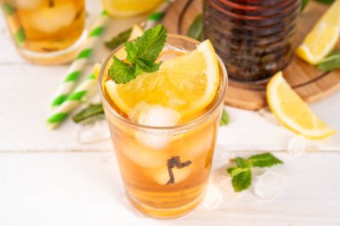 Buzlu çay kokteyli, soğuk yaz içeceği, siyah çay, limon, nane ve ezilmiş buz, beyaz ahşap arka planda alkolsüz hoş bir kokteyl. 