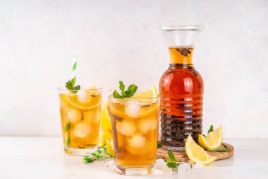 Iced tea cocktail drink, cold summer drink with black tea, lemon, mint and crushed ice, tasty refreshing non-alcohol mocktail on white wooden table background  clipart