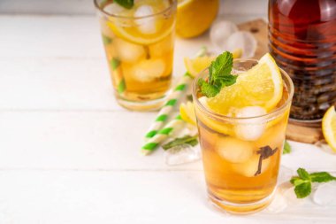 Buzlu çay kokteyli, soğuk yaz içeceği, siyah çay, limon, nane ve ezilmiş buz, beyaz ahşap arka planda alkolsüz hoş bir kokteyl. 