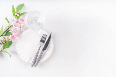 Paskalya bayramı sofrası, çatal bıçak takımı, tabak, bahar ağacı dalları, Paskalya yumurtası ve yuva süsü, beyaz masa arkası fotokopi alanı. Paskalya yemeği daveti, menü geçmişi