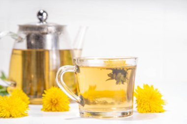 Dandelions plant herbal flower tea. Transparent glass cup and teapot with golden hot tea drink, on white background with dandelion flowers and leaves clipart