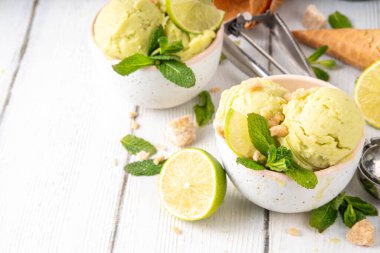 Yaz ferahlatıcı soğuk tatlı, lezzetli aromatik mojito veya limonlu turtalı dondurma, seramik kasede mojito kokteyli aromalı ev yapımı şerbet, taze limon, nane, ahşap zemin üzerinde waffle konileri.