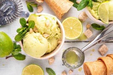 Yaz ferahlatıcı soğuk tatlı, lezzetli aromatik mojito veya limonlu turtalı dondurma, seramik kasede mojito kokteyli aromalı ev yapımı şerbet, taze limon, nane, ahşap zemin üzerinde waffle konileri.